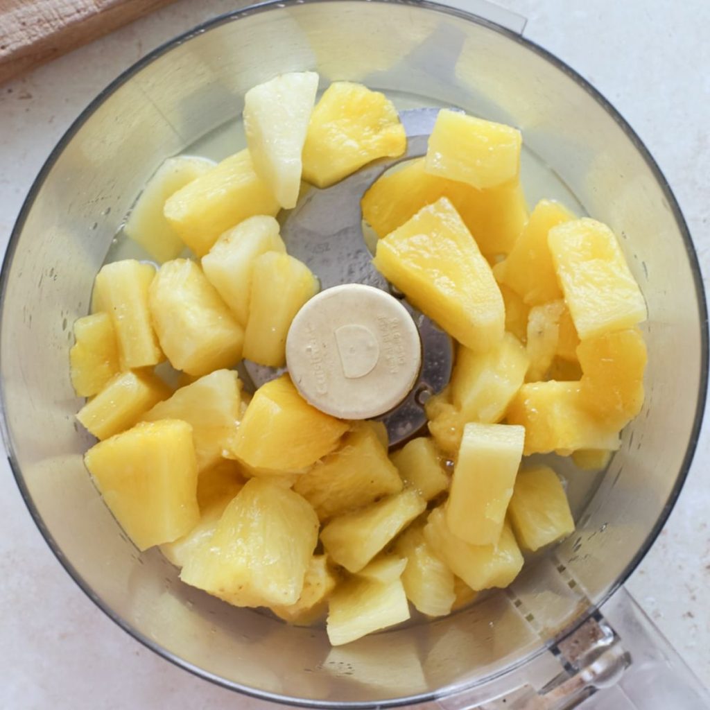 Frozen pineapple chunks in a food processor bowl to make jam.