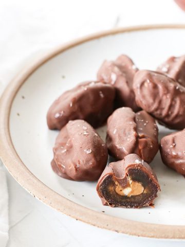 A plate of homemade chocolate covered date snickers.