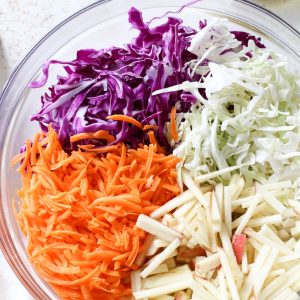 coleslaw ingredients in a bowl with a side of dressing no mayo