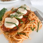 Gluten-free chicken parmesan over spaghetti and marinara with fresh basil