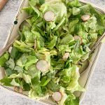 Butter leaf lettuce salad on a platter with sliced radishes and breadcrumbs.