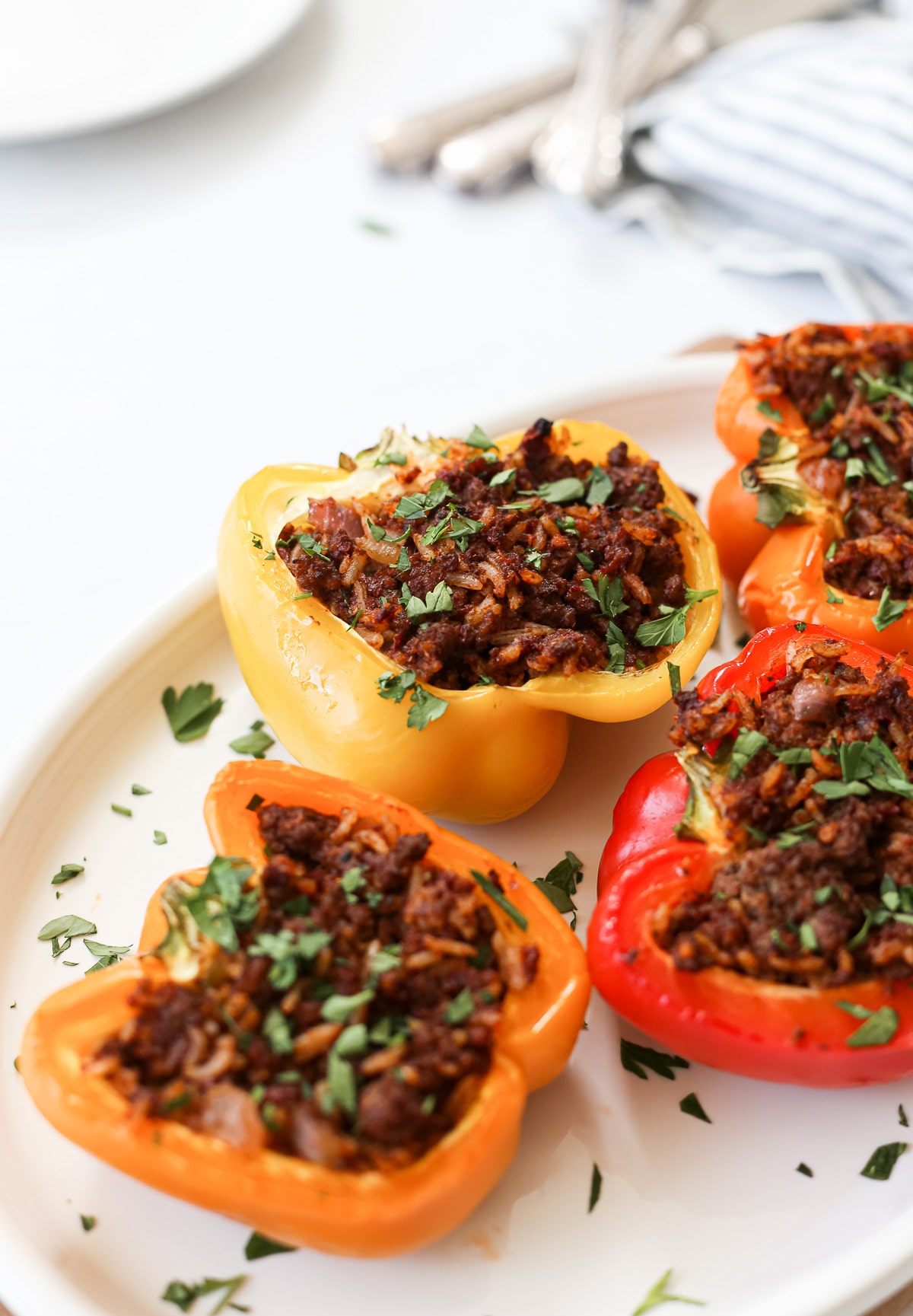 Colorful dairy-free stuffed peppers on a serving platter topped with chopped parsley.