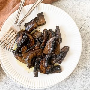 A plate full of marinaded portobello mushrooms with dried herbs.