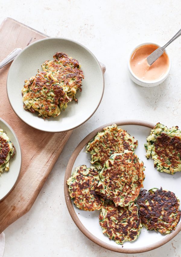 A spread of savory zucchini pancakes with a side of dipping sauce.