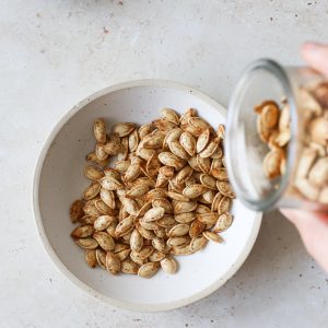 pouring roasted pumpkin seeds into a serving dish