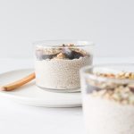 A short glass of overnight chia seed pudding topped with fresh fig slices and dukkah seasoning.