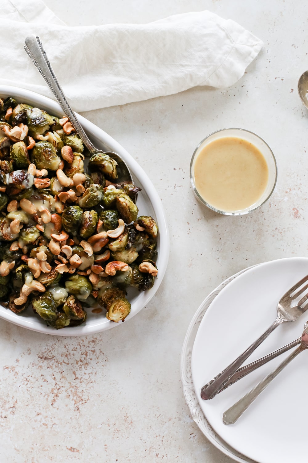 Serving plate with Asian Brussels sprouts drizzled with a creamy lemon miso dressing.