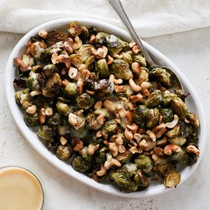 serving plate with roasted Brussels sprouts drizzled with a creamy lemon miso sauce