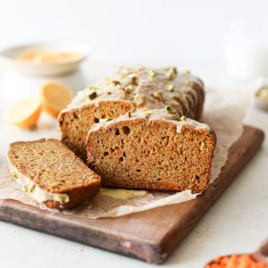 Sliced carrot cake loaf with a citrus glaze and chopped pistachios.