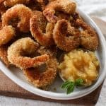 An oval plate of homemade gluten free coconut shrimp served with pineapple jam.