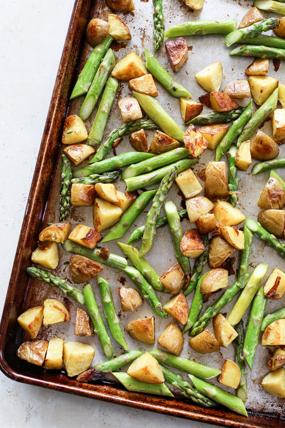 Roasted asparagus and potatoes on a baking sheet.