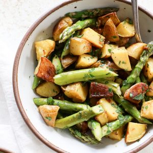 A large bowl of potato and asparagus salad with roasted garlic dressing.