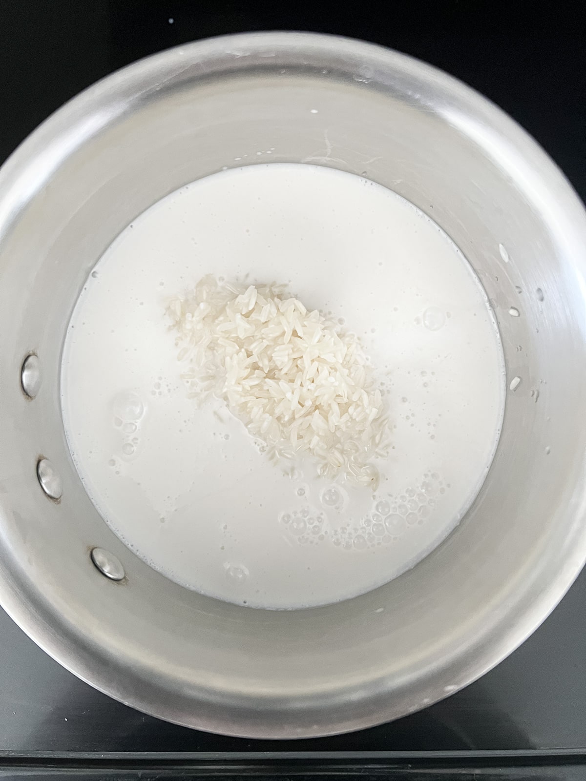 Coconut milk, rice, water, and salt in a saucepan.