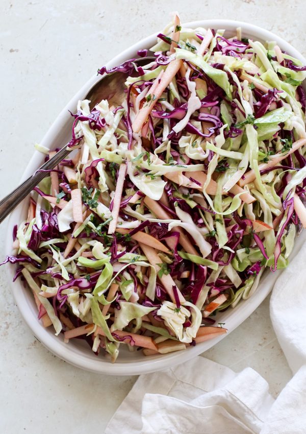 An oval platter or red and green cabbage salad with apples.