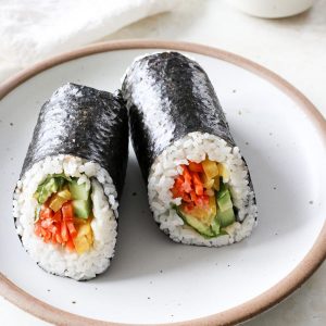 Two sushi burrito halves on a plate.