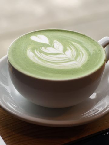 A warm matcha latte with a beautiful heart latte art on top.