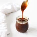 A spoonful of soy-free teriyaki sauce dripping off a spoon into the jar.