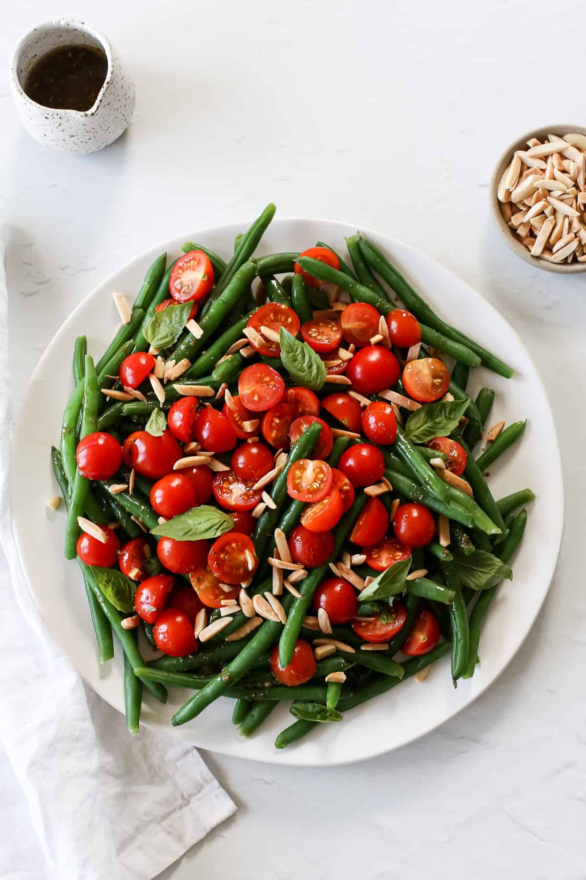 A colorful Italian green bean salad with cherry tomatoes, toasted almonds, and fresh basil leaves.