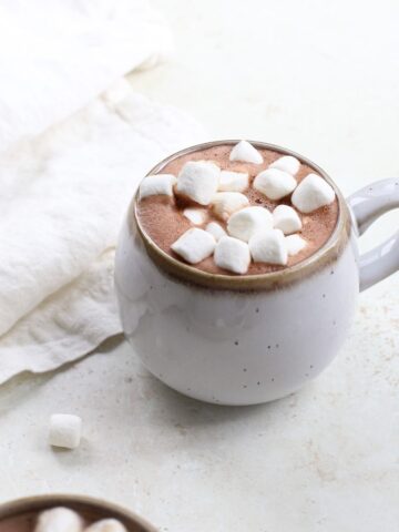 A mug of dairy free oat milk hot chocolate with mini marshmallows.